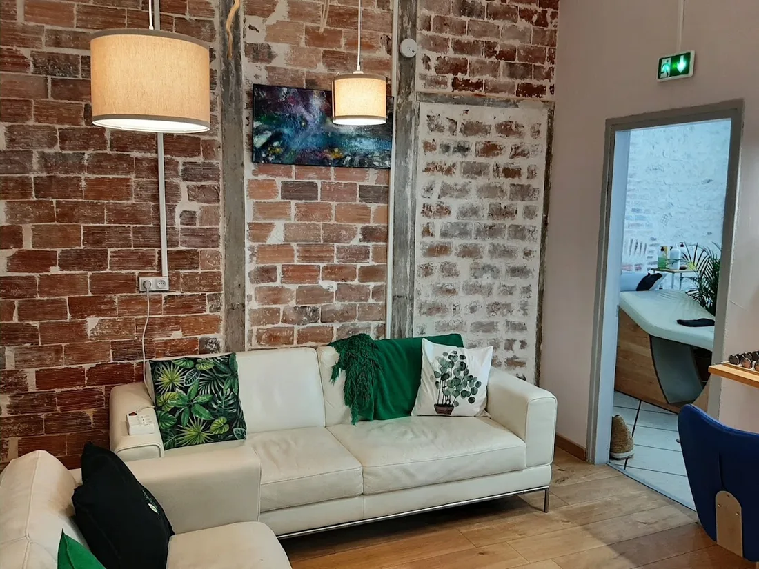 L’intérieur du salon Le Peigne Vert à Orléans, avec ses murs en briques et son espace d’accueil.